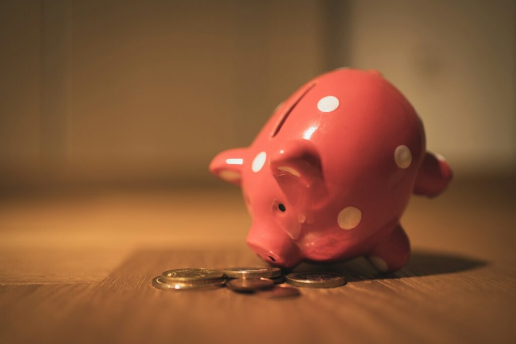 Ein rosa Sparschwein und ein paar Münzen auf einem Holztisch