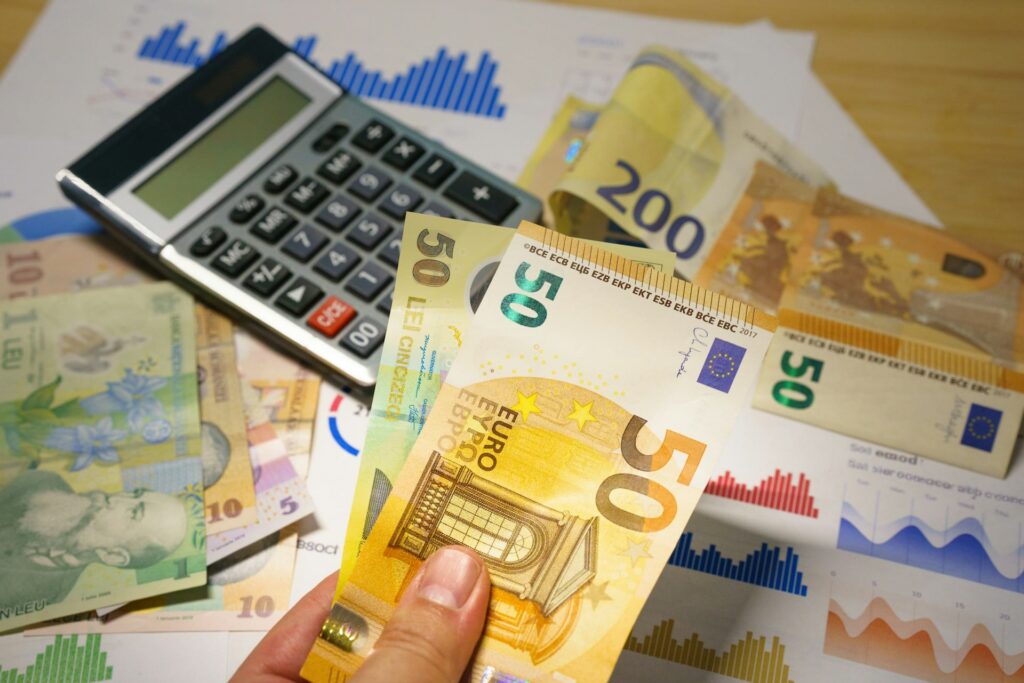 Eine Person, die Geldscheine neben einem Taschenrechner in der Hand hält