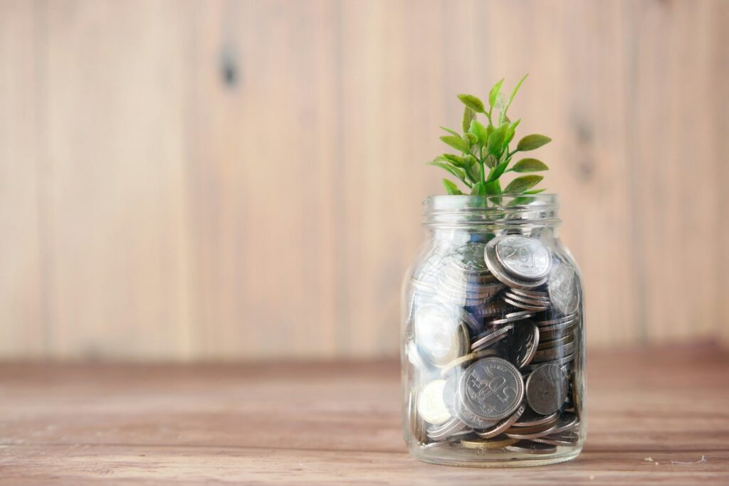Symbolbild für „in Fonds investieren“ – Ein Glas mit Münzen und wachsender Pflanze steht für langfristigen Vermögensaufbau und nachhaltiges Investment.