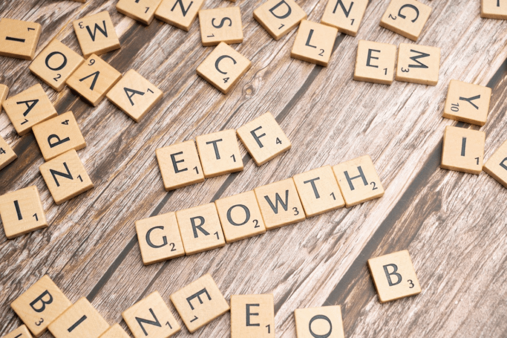 Holz-Spielsteine mit Buchstaben bilden die Wörter „ETF“ und „Growth“ auf einem Holztisch – Symbolbild für langfristiges Wachstum mit ETFs, egal ob thesaurierend oder ausschüttend.